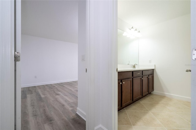 bathroom with hardwood / wood-style flooring, vanity, and lofted ceiling