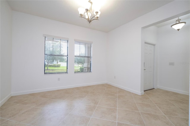 empty room with light tile patterned floors and a notable chandelier