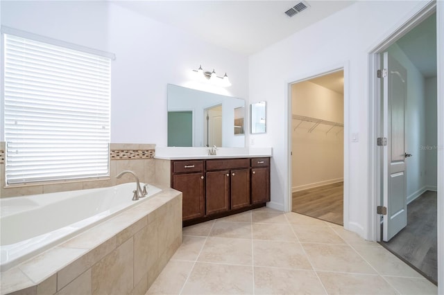 bathroom with tiled tub, vanity, and hardwood / wood-style flooring