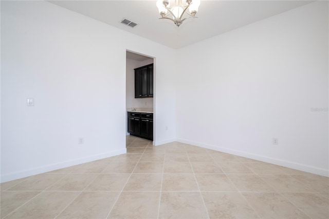 spare room featuring light tile patterned floors and an inviting chandelier