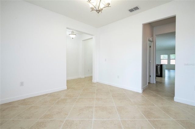 tiled empty room featuring an inviting chandelier