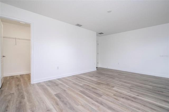 unfurnished bedroom featuring light wood-type flooring, a spacious closet, and a closet