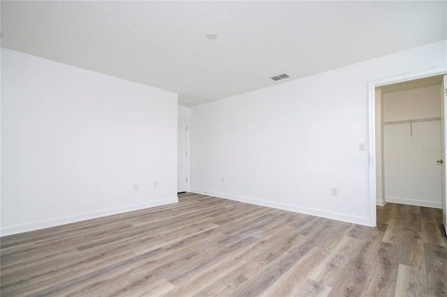 unfurnished bedroom with a closet, a spacious closet, and light hardwood / wood-style flooring