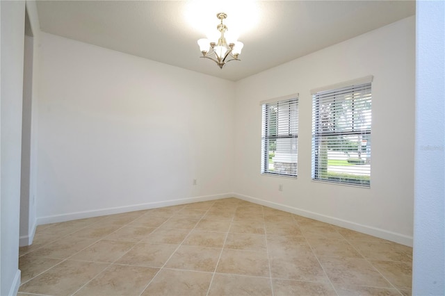 tiled spare room with a notable chandelier