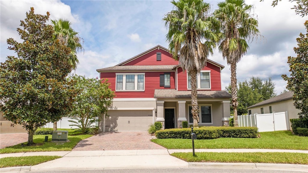 view of front of home with an attached garage, fence, decorative driveway, stucco siding, and a front lawn