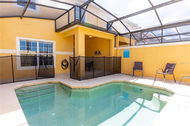 view of pool with glass enclosure and a patio area