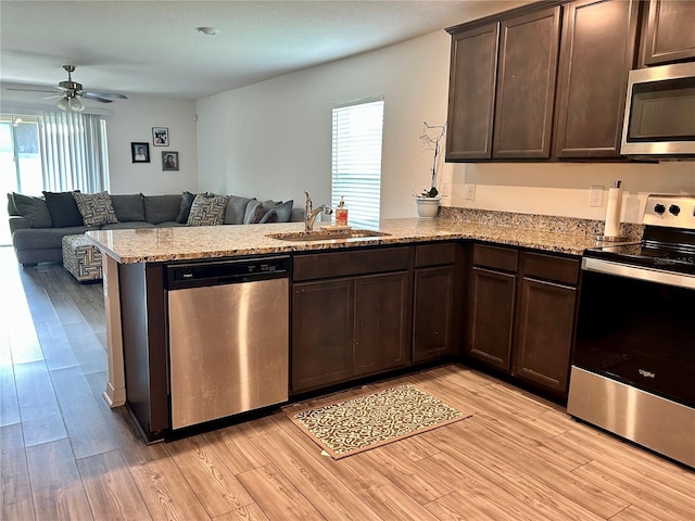 kitchen featuring a wealth of natural light, stainless steel appliances, light hardwood / wood-style floors, and kitchen peninsula