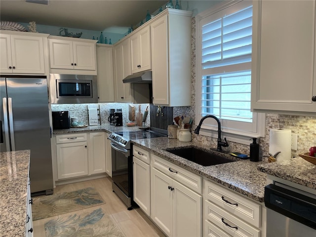 kitchen featuring white cabinets, light stone counters, sink, and appliances with stainless steel finishes