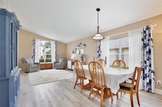 dining area featuring vaulted ceiling and light hardwood / wood-style floors