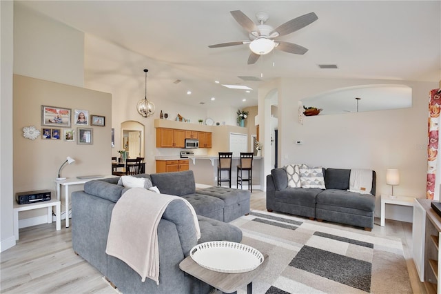 living room featuring ceiling fan with notable chandelier, light wood-type flooring, and high vaulted ceiling