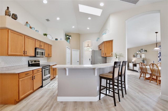 kitchen with light wood-type flooring, a skylight, stainless steel appliances, and high vaulted ceiling