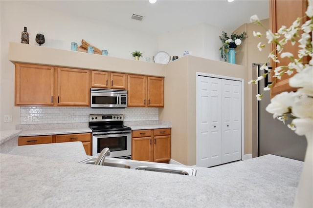 kitchen featuring a high ceiling, stainless steel appliances, sink, and decorative backsplash