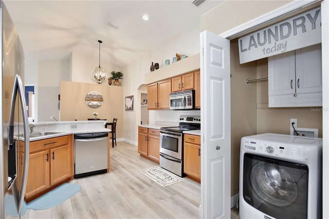 kitchen with light wood-type flooring, washer / clothes dryer, a chandelier, appliances with stainless steel finishes, and decorative light fixtures