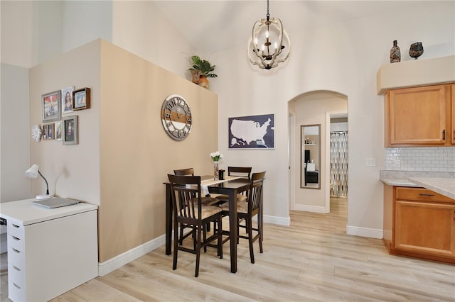 dining room with light hardwood / wood-style flooring, a notable chandelier, and high vaulted ceiling