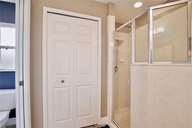 bathroom with a shower with shower door and toilet