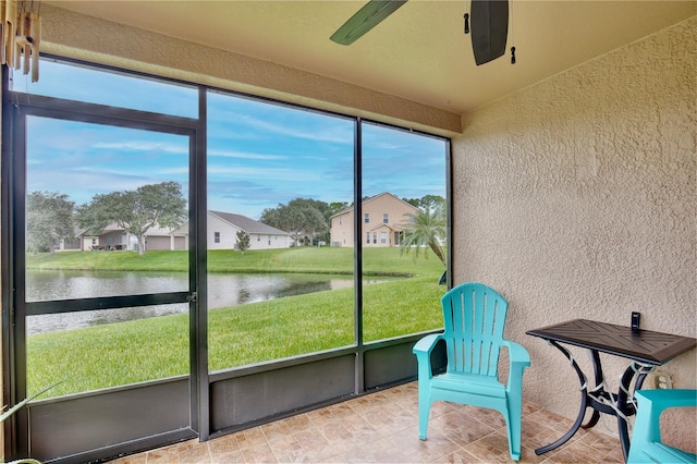 sunroom featuring a water view and ceiling fan