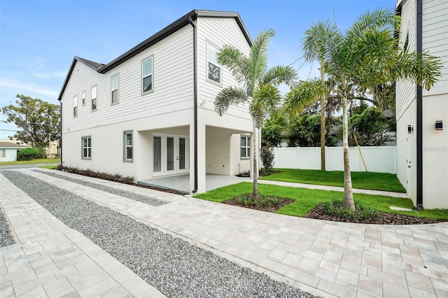 back of property featuring a lawn, a patio, and french doors