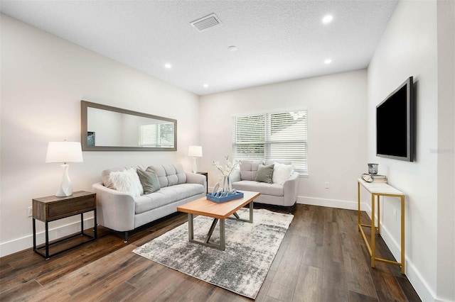 living room with a textured ceiling and dark hardwood / wood-style flooring