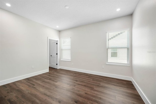 empty room with a textured ceiling and dark hardwood / wood-style floors