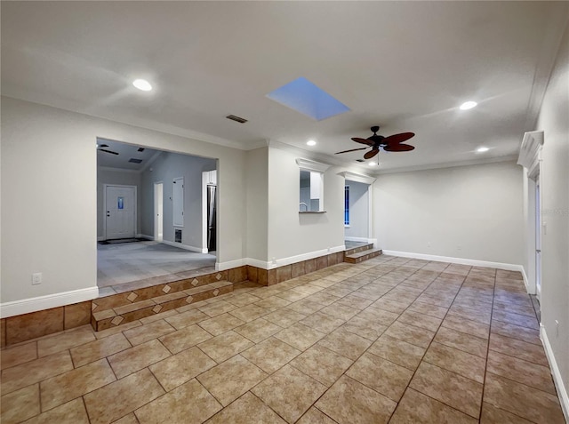 unfurnished room featuring light tile patterned flooring, ceiling fan, ornamental molding, and a skylight