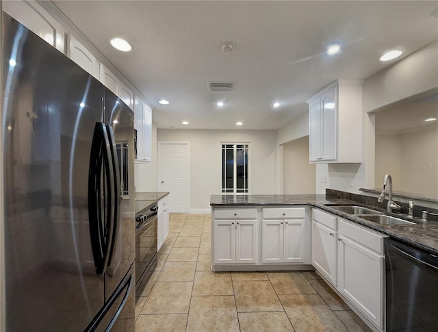 kitchen featuring appliances with stainless steel finishes, kitchen peninsula, sink, white cabinetry, and dark stone countertops