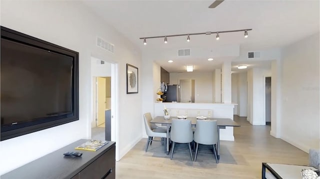 dining room with rail lighting and light hardwood / wood-style floors