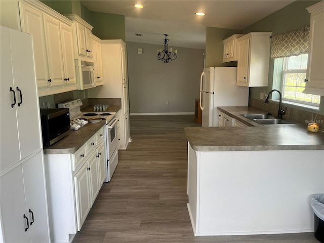 kitchen featuring dark wood-type flooring, kitchen peninsula, sink, white cabinetry, and white appliances