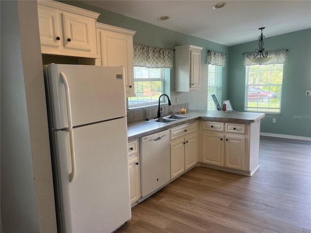 kitchen featuring white appliances, sink, kitchen peninsula, and white cabinets