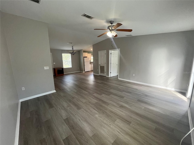 unfurnished living room with ceiling fan with notable chandelier, vaulted ceiling, and dark hardwood / wood-style floors