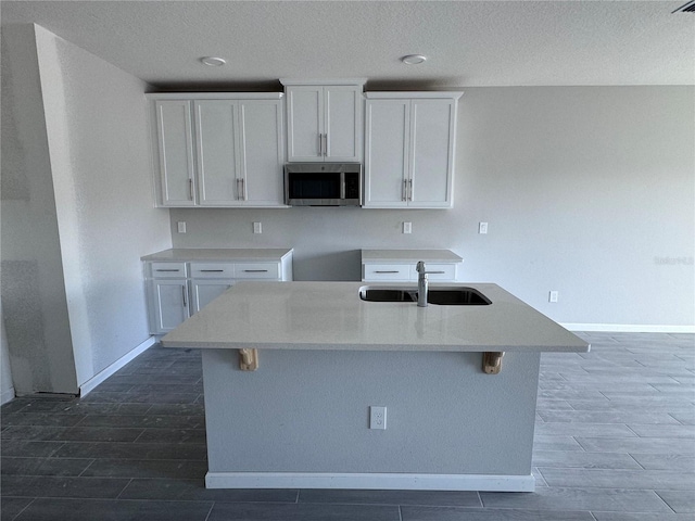 kitchen featuring white cabinetry, sink, and an island with sink