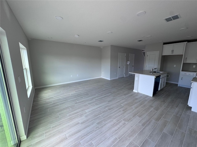 kitchen with white cabinetry, sink, an island with sink, and light hardwood / wood-style floors