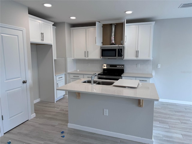 kitchen featuring a center island with sink, sink, white cabinetry, and stainless steel appliances