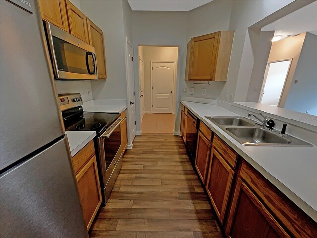 kitchen featuring appliances with stainless steel finishes, sink, and light hardwood / wood-style floors