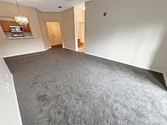 unfurnished living room featuring a chandelier and dark colored carpet