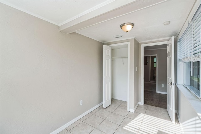 unfurnished bedroom with crown molding, a closet, and light tile patterned flooring