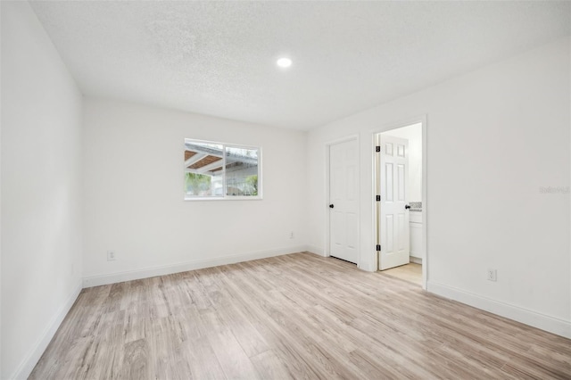 unfurnished room with light wood-type flooring and a textured ceiling