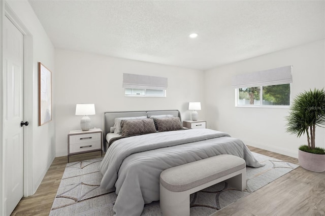 bedroom with a textured ceiling and light hardwood / wood-style flooring