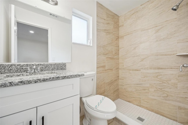 bathroom with vanity, toilet, and tiled shower