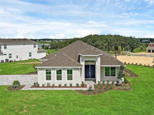 view of front of property with central AC unit, stucco siding, a shingled roof, and a front yard