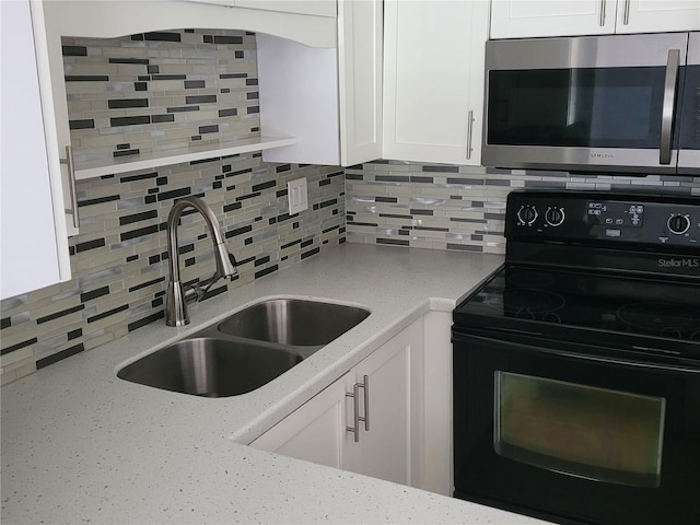 kitchen featuring black electric range oven, white cabinetry, light stone countertops, and sink