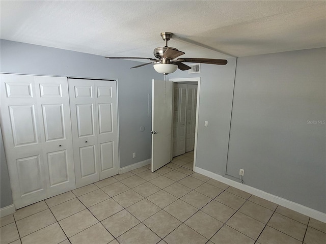 unfurnished bedroom featuring a textured ceiling, light tile patterned floors, and ceiling fan