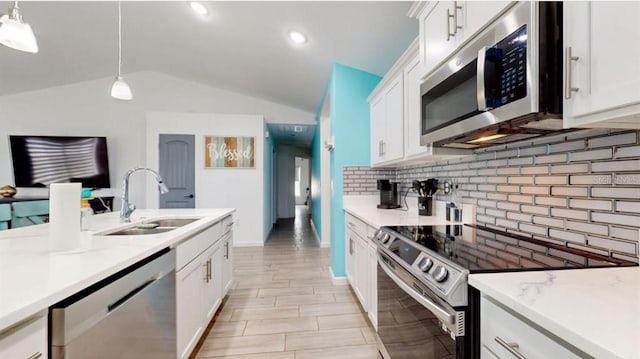 kitchen with appliances with stainless steel finishes, lofted ceiling, sink, and hanging light fixtures