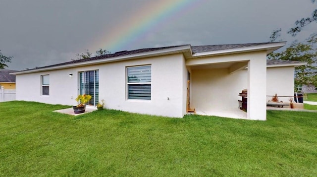 rear view of house featuring a lawn and a patio