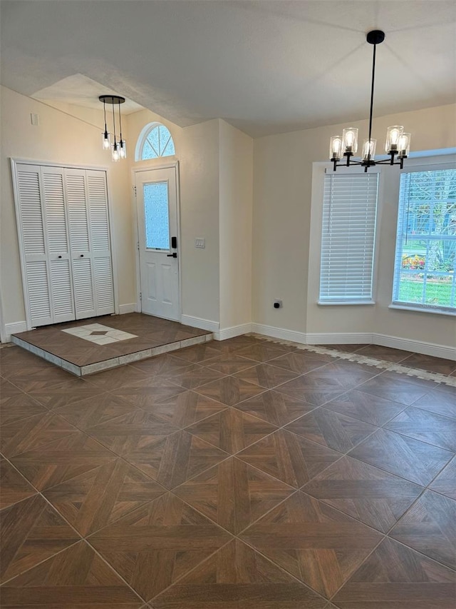 foyer entrance featuring dark parquet floors and an inviting chandelier