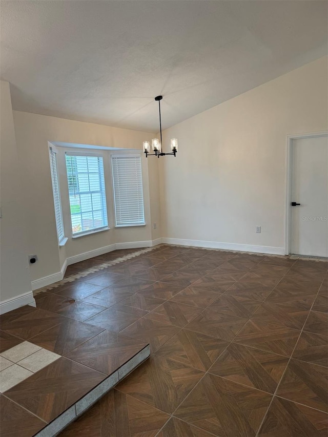 spare room with dark parquet flooring and a notable chandelier