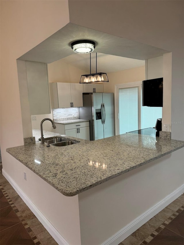 kitchen with white cabinets, sink, hanging light fixtures, light stone counters, and kitchen peninsula