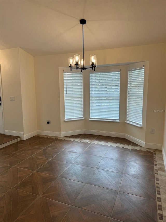 unfurnished room featuring a chandelier