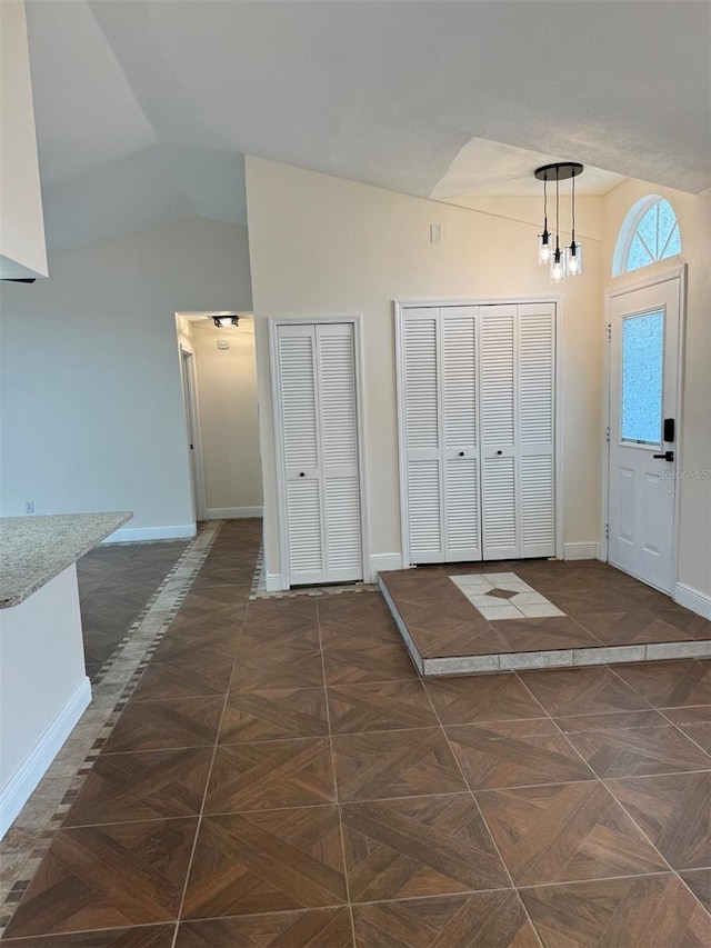 entryway featuring dark parquet floors and lofted ceiling