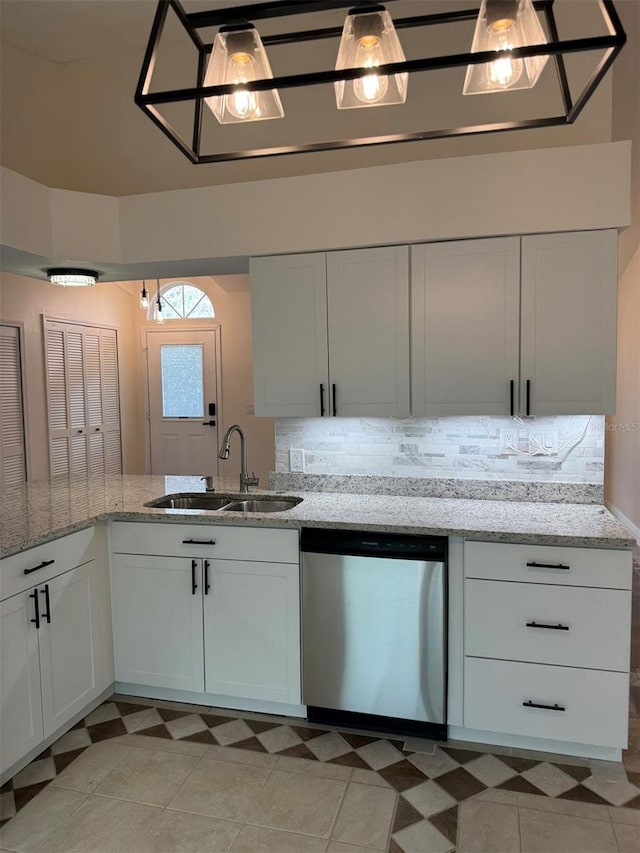 kitchen with dishwasher, sink, light stone countertops, light tile patterned floors, and white cabinetry