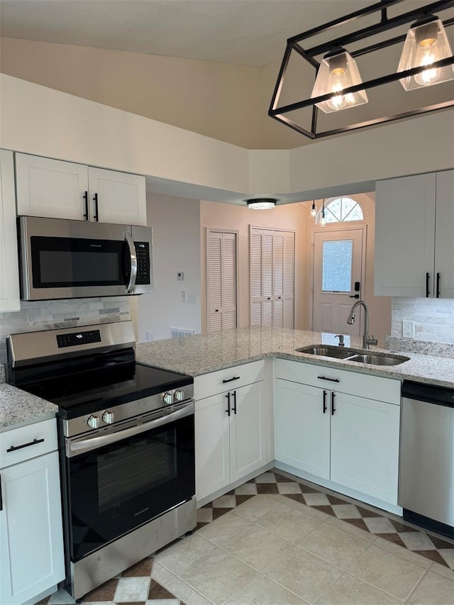 kitchen with vaulted ceiling, stainless steel appliances, white cabinetry, and sink